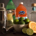 Photo of limes, grapefruit, grapefruit juice, lime juice, tequila, and fresca next to a cocktail shaker