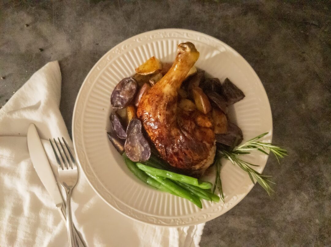 Chicken leg on a bed of roasted potatoes and green beans