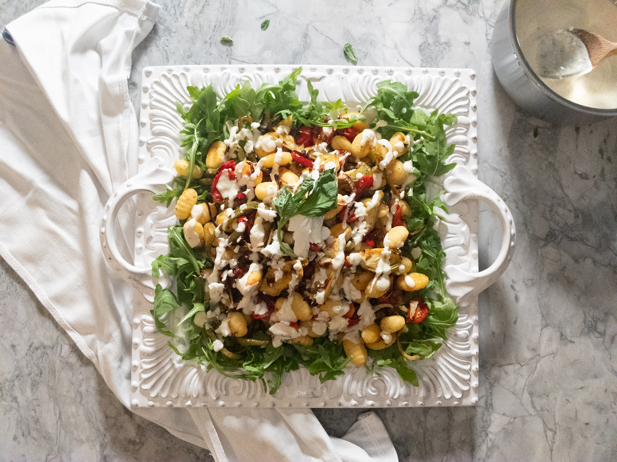 Overhead shot of roasted gnocchi and vegetables on a bed of arugula