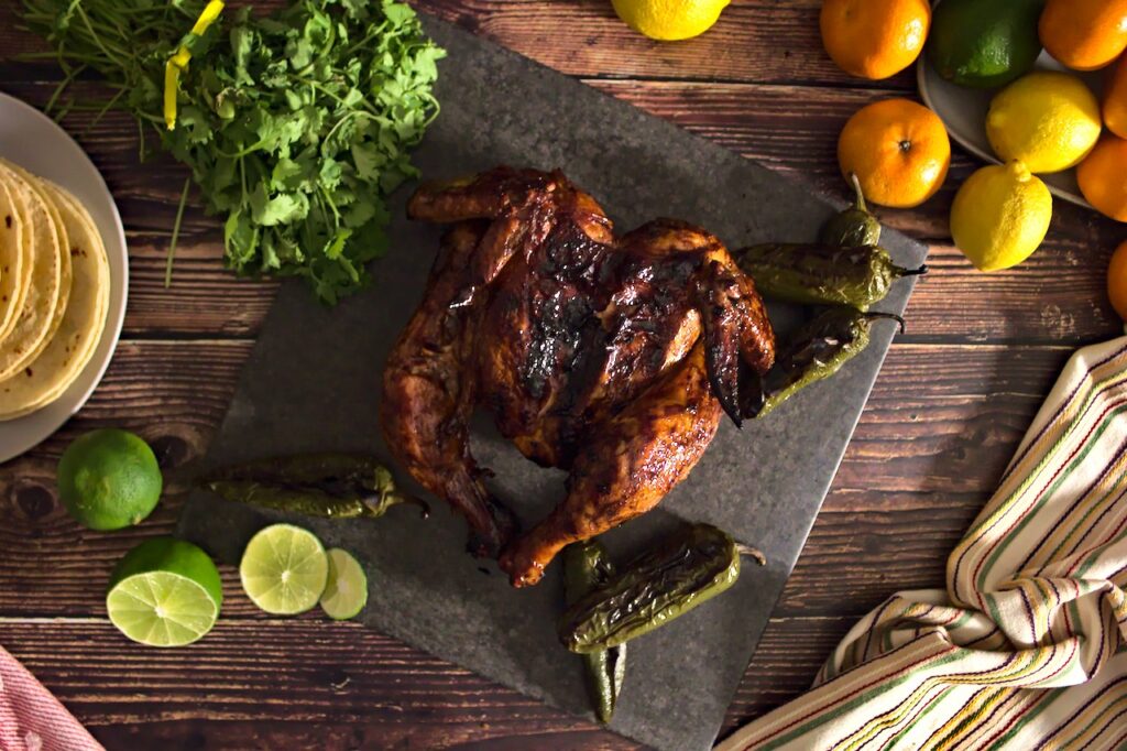 Overhead shot of whole grilled chicken surrounded by roasted jalepenos