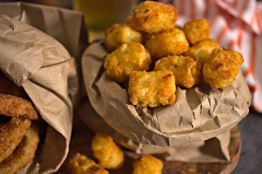 Closeup photo of crispy tater tots and onion rings