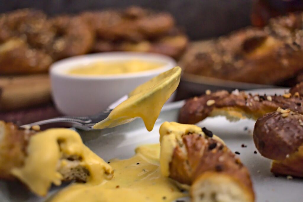 Closeup photo of beer cheese dip on a spoon surrounded by pretzels