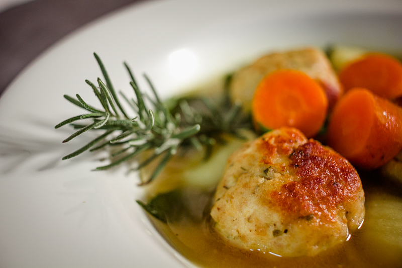 Closeup photo of lemony Italian wedding soup with a sprig of rosemary